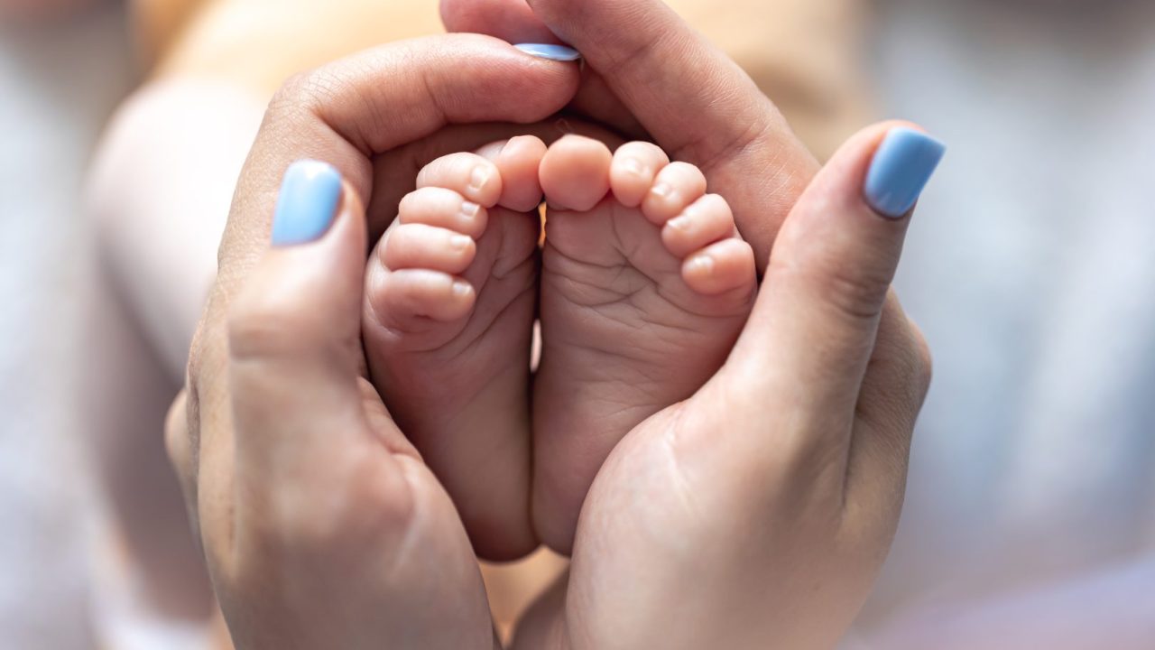 mamae-segura-as-pernas-de-um-bebe-recem-nascido-em-suas-maos