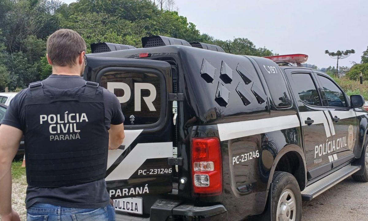 Viatura da Polícia Civil do Paraná estacionada na rua com um policial civil fechando o porta-malas do veículo