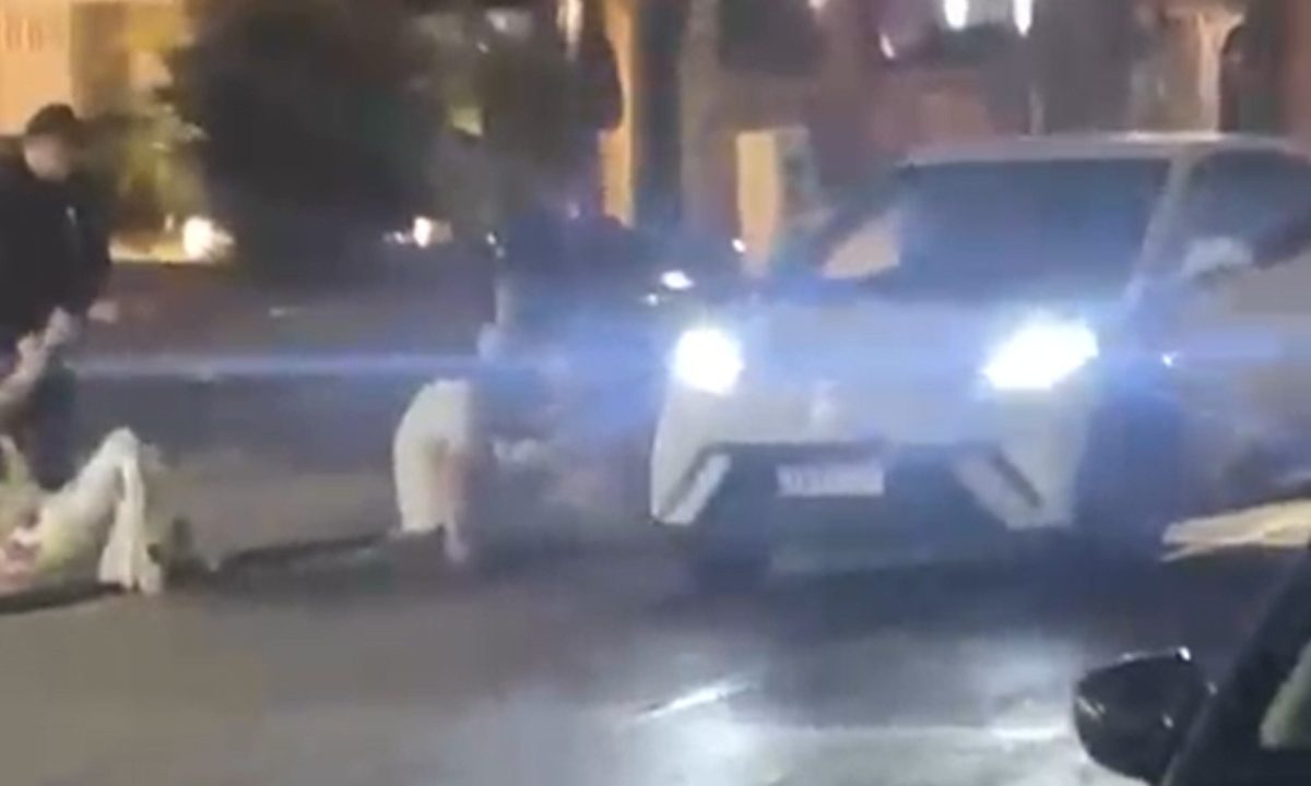 Carro do homem suspeito do atropelamento parado no meio da rua enquanto as vítimas estão caídas na calçada no bairro Batel, em Curitiba