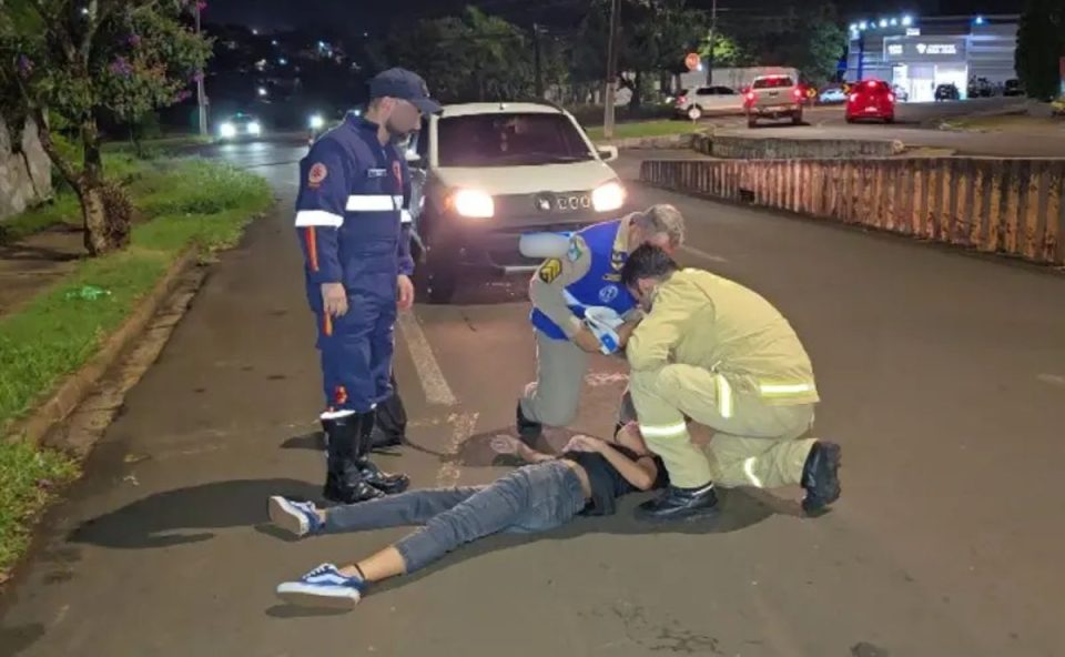Adolescente que foi atropelada pelo socorrista do Samu deitada no chão da avenida enquanto recebe atendimento