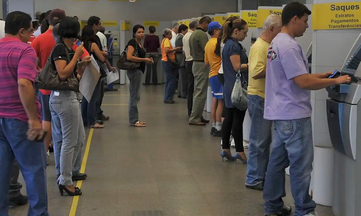 Fila de pessoas aguardando atendimento em caixas eletrônicos