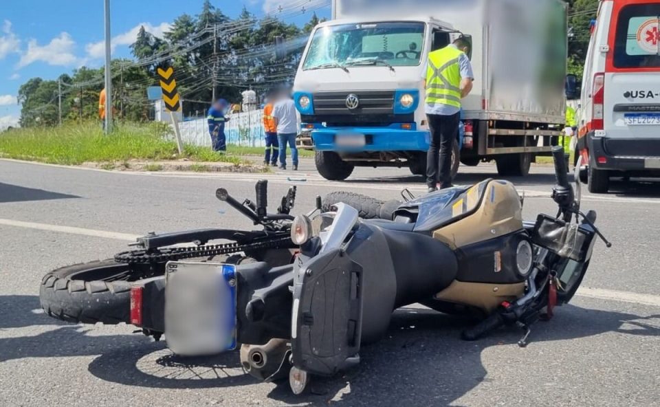 Moto caída no asfalto, socorristas e caminhão parado na rua