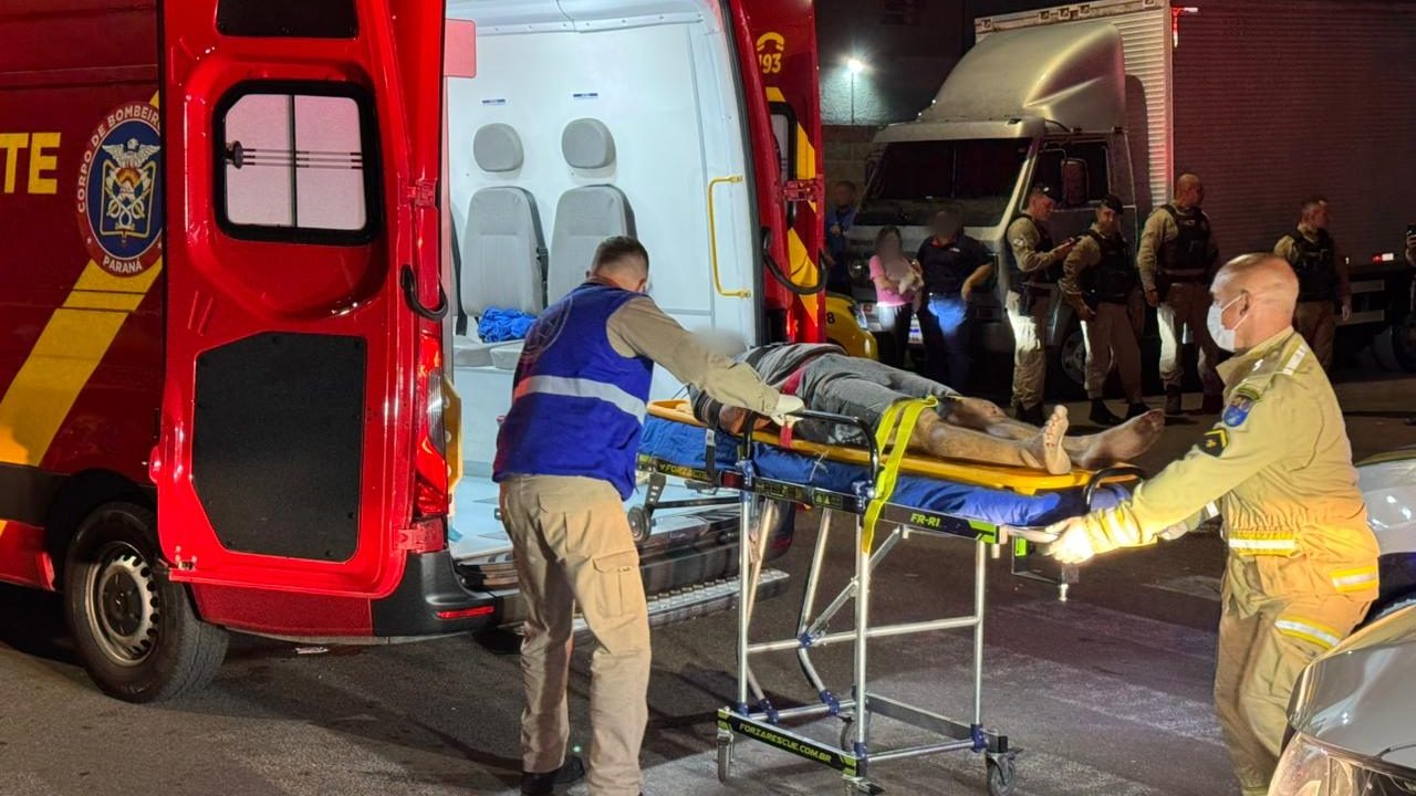 Foto mostra um dos envolvidos na confusão em uma maca e sendo colocado dentro de ambulância do Corpo de Bombeiros; testemunhas acompanham atendimento