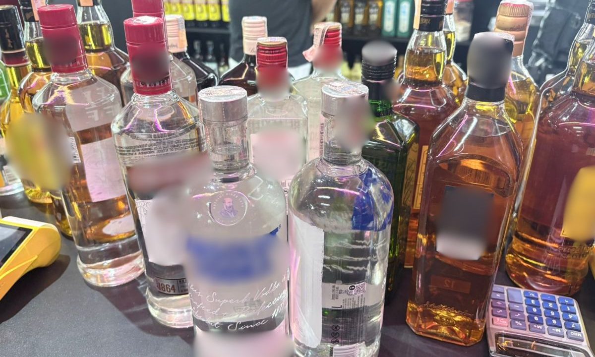 Garrafas de bebidas alcoólicas, como gins e vodcas, com sinais de adulteração