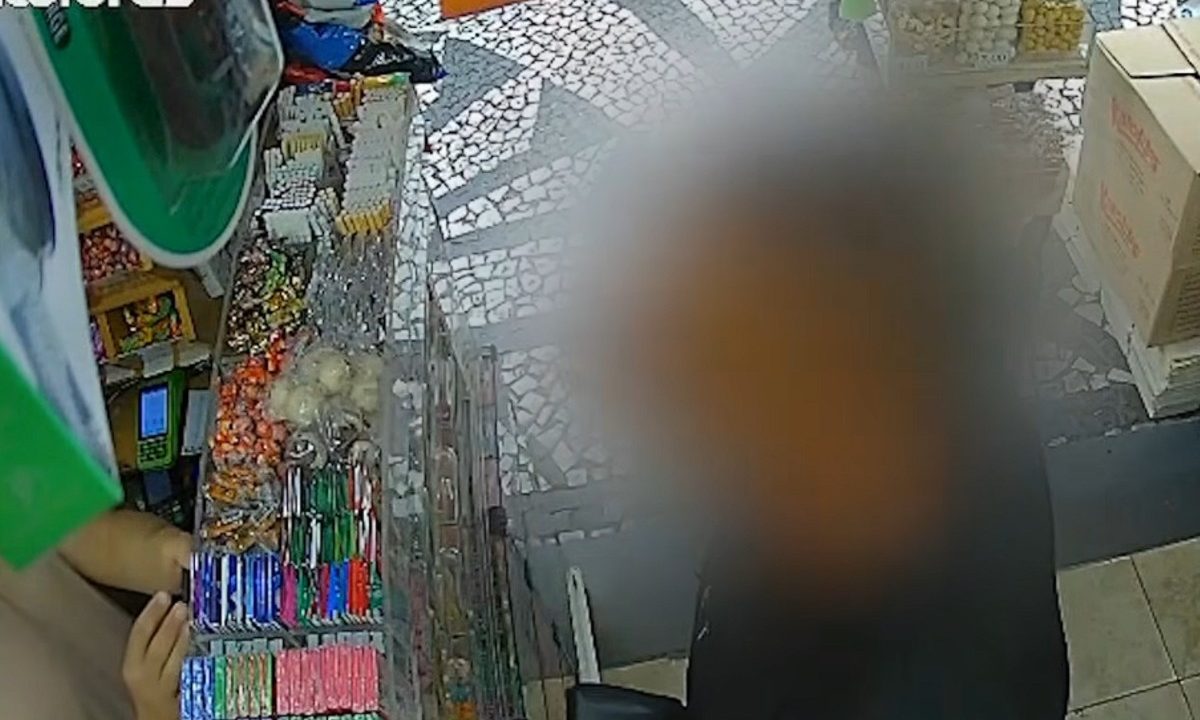 Uma imagem de um homem com o rosto borrado para não identificar conversando com um comerciante em um comércio no Centro de Curitiba