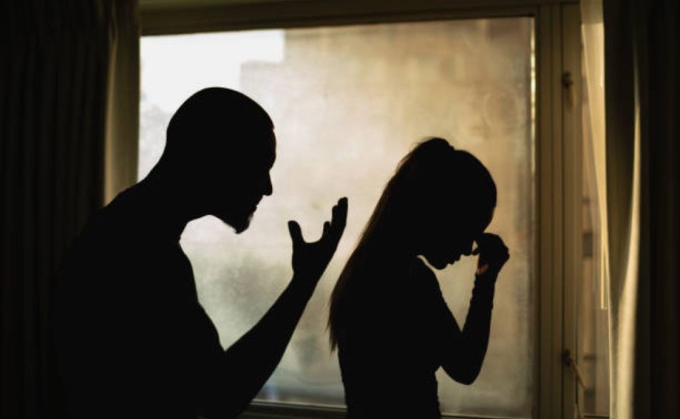 Silhuetas de homem e mulher discutindo dentro de casa