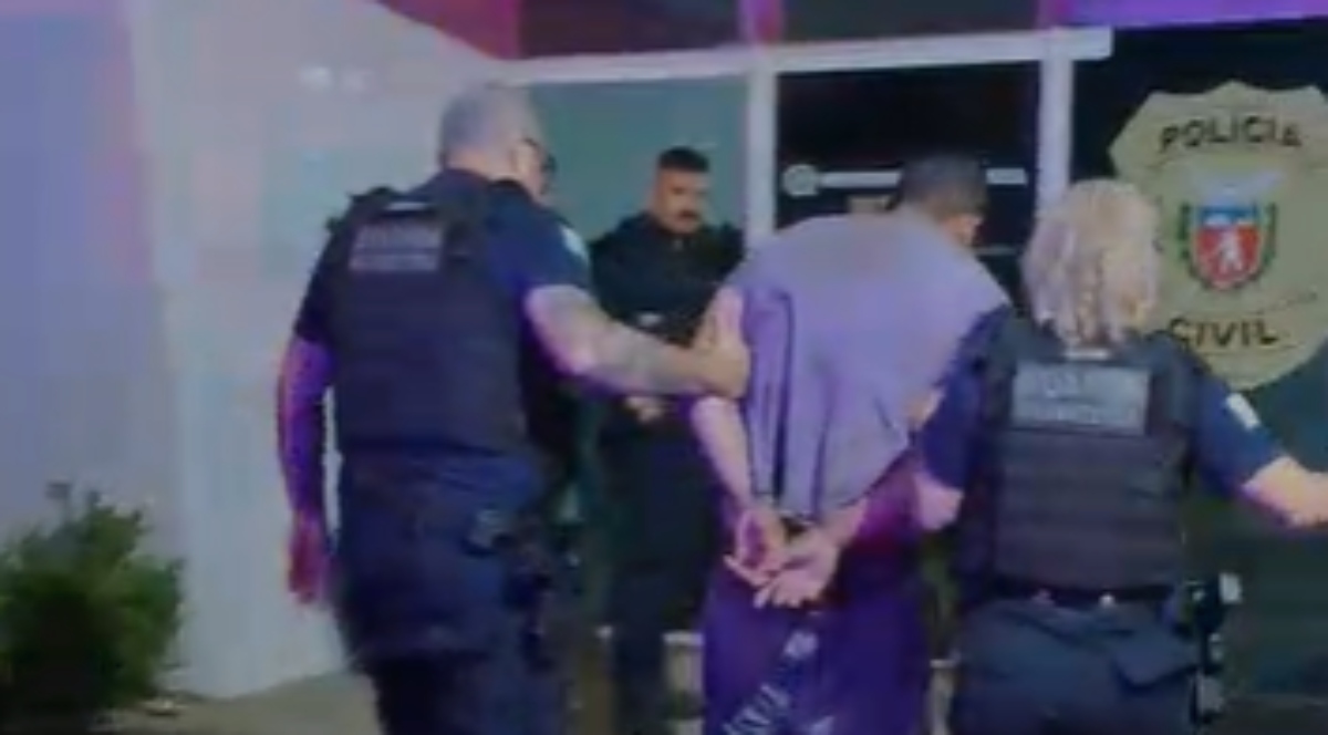 Homem sendo algemado por agentes da Guarda Municipal em rua residencial após invadir casa em Fazenda Rio Grande.