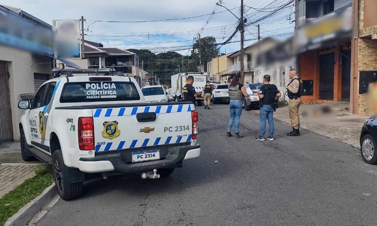 Carro da Polícia Científica e policiais em local de crime