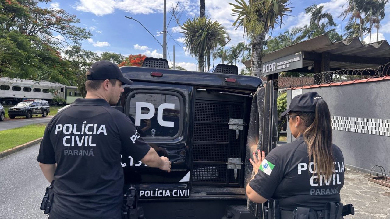 Foto mostra dois policiais – um homem e uma mulher – fechando compartimento traseiro de viatura da Polícia Civil do Paraná