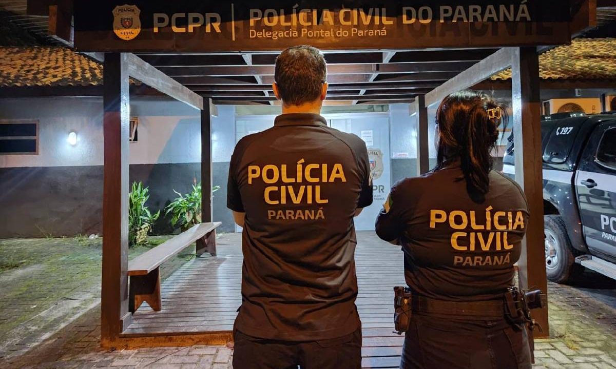 Foto mostra dois policiais parados em frente a uma delegacia