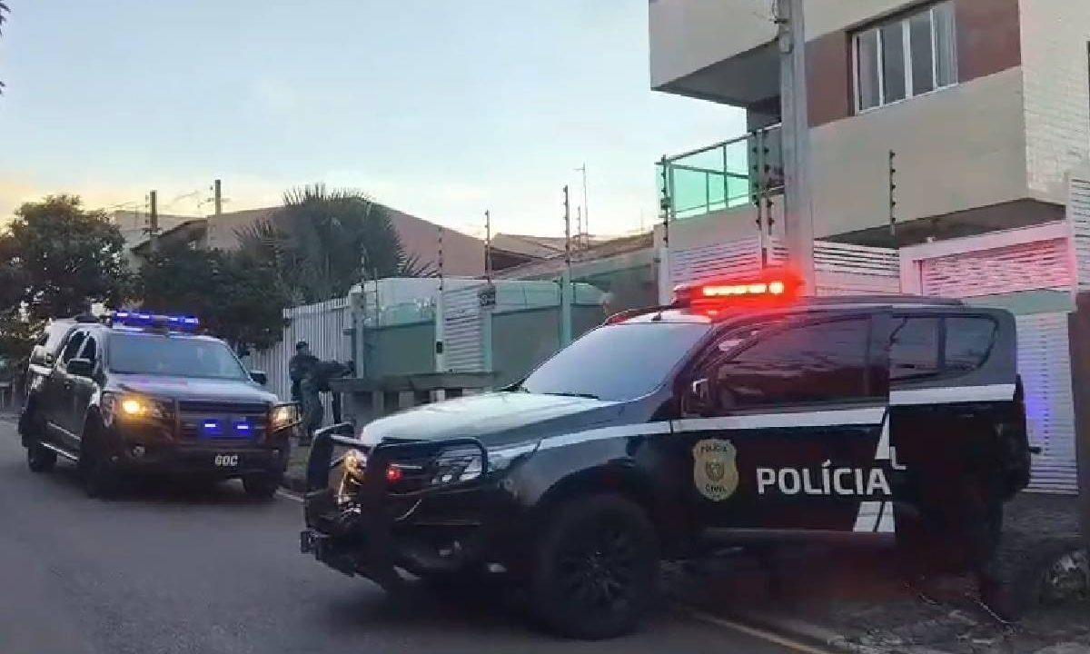 Foto mostra viaturas da Polícia Civil paradas em frente ao prédio do suspeito