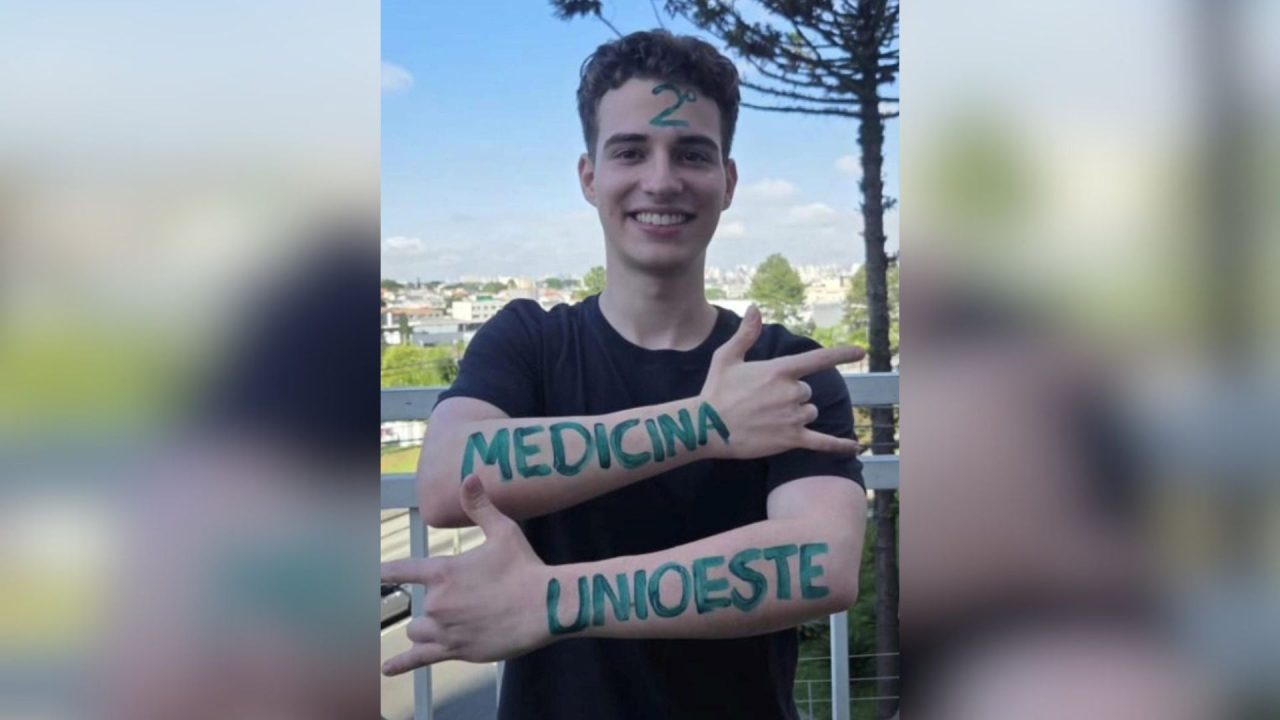 Foto mostra estudante sorrindo, com o número 2 pintado na tenta e as palavras "medicina" e "Unioeste" desenhados nos braços