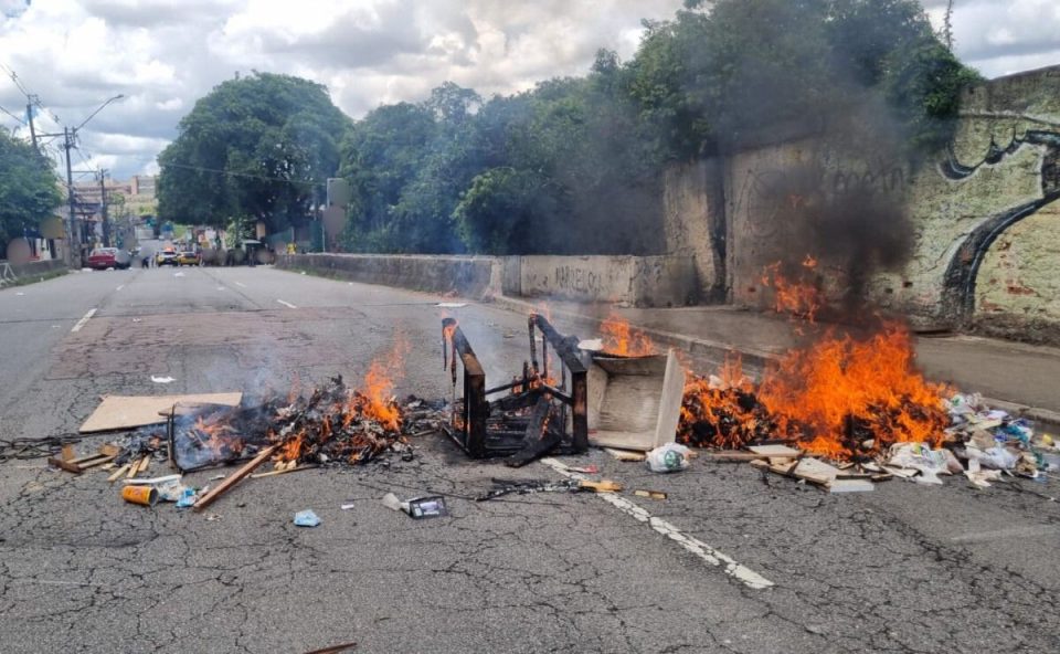 Objetos pegando fogo fechando rua após confronto
