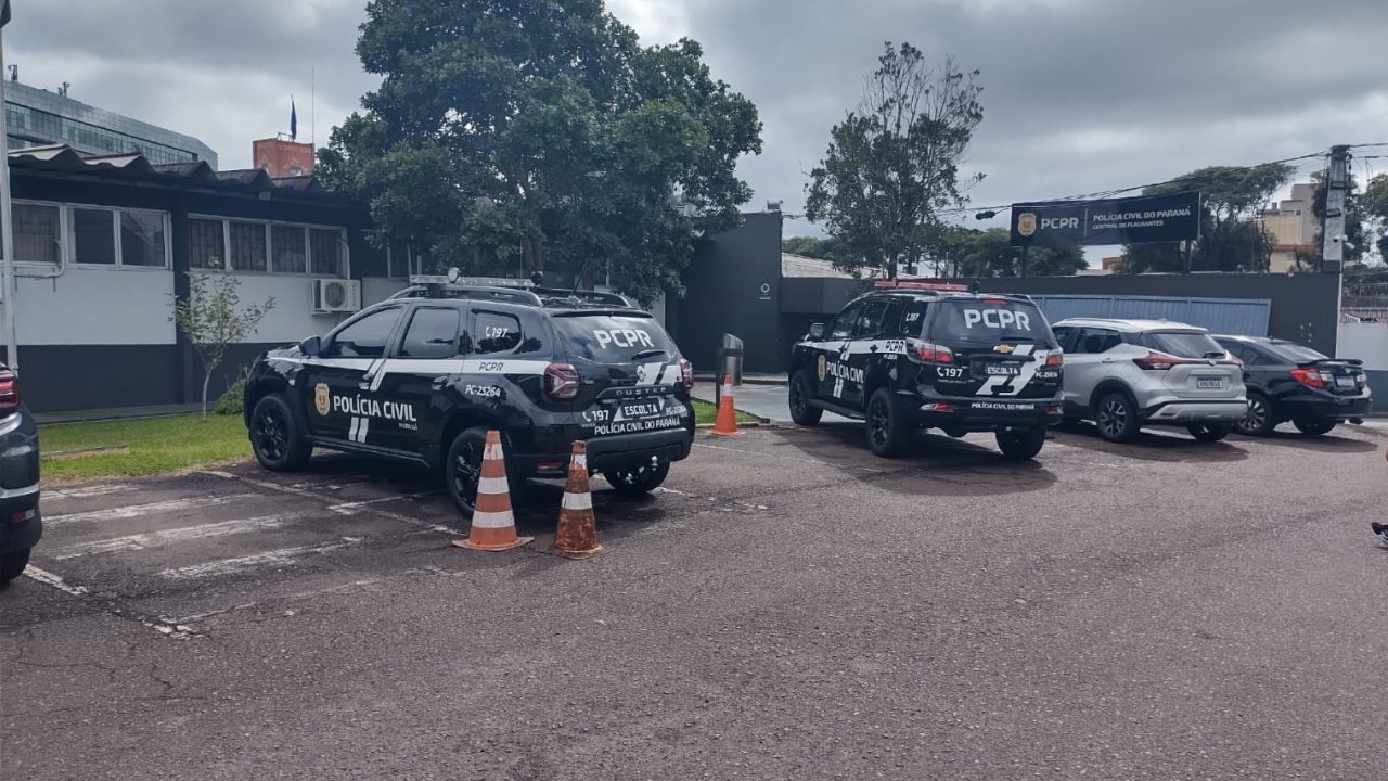 Foto mostra fachada da Central de Flagrantes da Polícia Civil, no bairro Portão, em Curitiba. Viaturas da corporação aparecem estacionadas em frente ao prédio