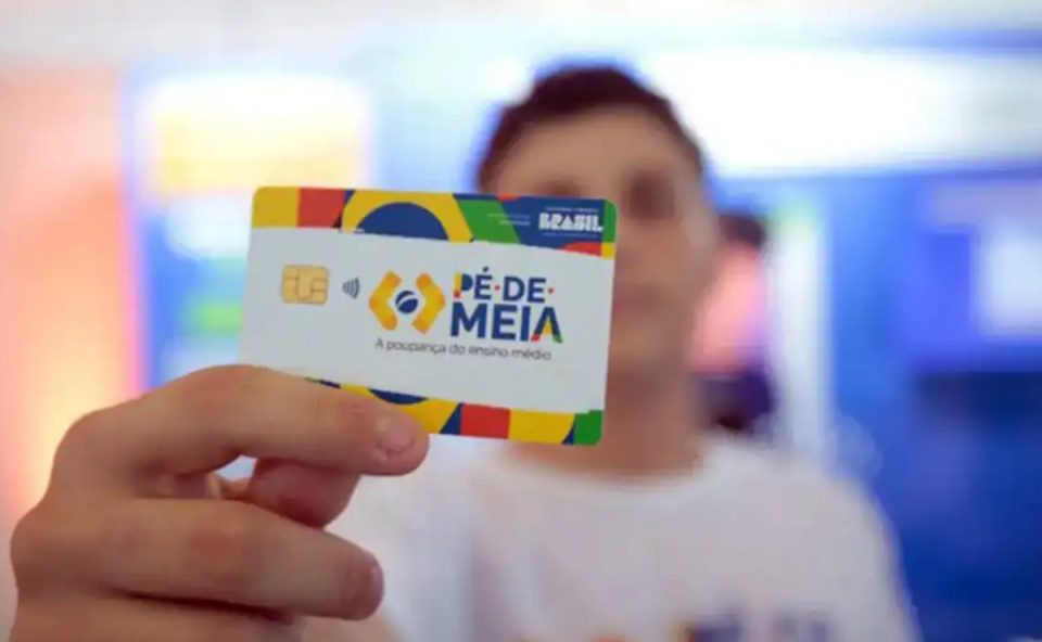 Foto de jovem segurando um cartão do Pé-de-Meia