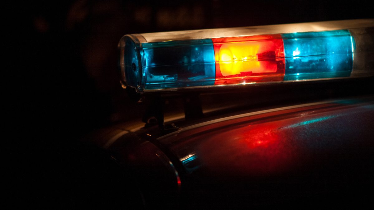 Foto ilustrativa de banco de imagens mostra sirene de viatura policial com luz ligada; as cores são azul e vermelho, com fundo preto