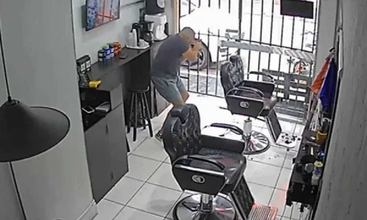 Foto capturada de vídeo registrado por câmera de segurança mostra policial de folga atirando contra suspeito de assalto em São Paulo. Ele está em uma barbearia.