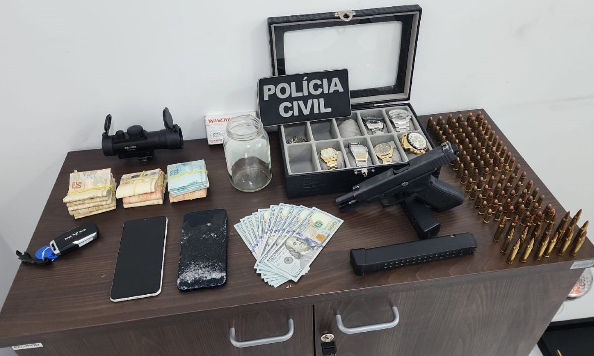 Celulares, dinheiro, drogas, armas de fogo, munições e relógios em cima da mesa após apreensão