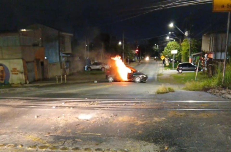 Carro em chamas na Rua dos Ferroviários durante protesto após confronto policial no Cajuru, em Curitiba