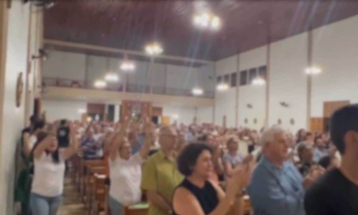 foto de igreja cheia com pessoas batendo palmas