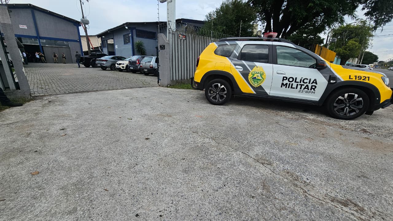 Viatura da Polícia Militar em frente a um barracão na Cidade Industrial de Curitiba onde trabalhador sofreu queda de telhado.