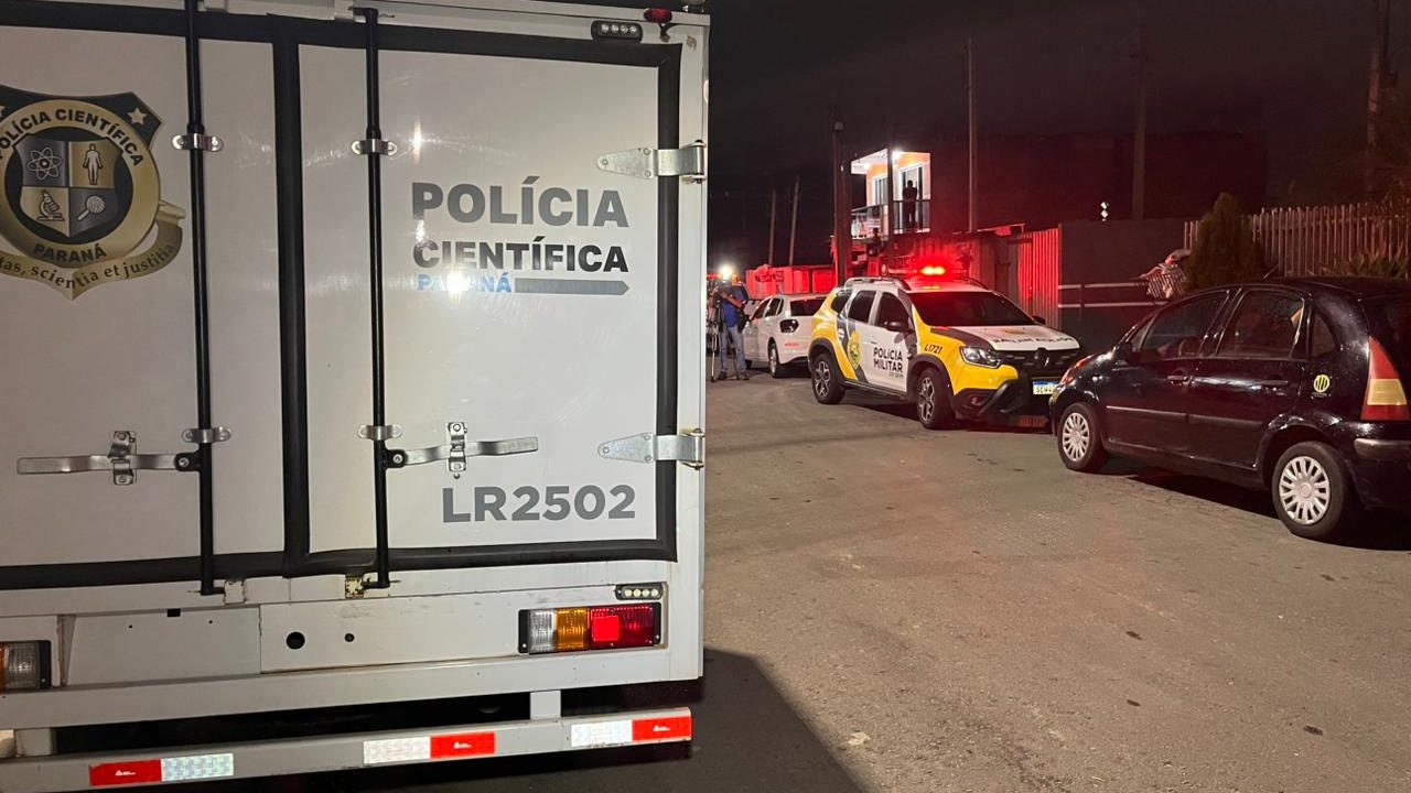 Foto tirada à noite mostra viaturas da Polícia Militar e da Polícia Científica estacionadas em frente ao pensionato onde trabalhador foi assassinado