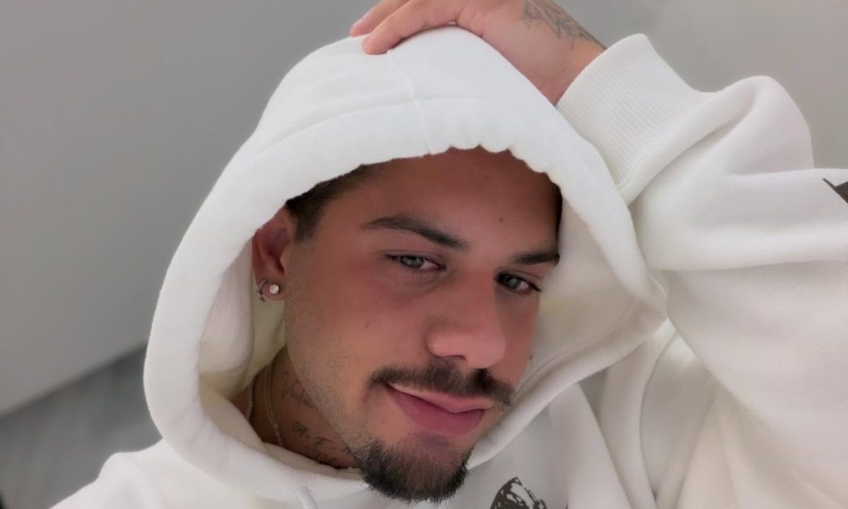 O cantor Zé Felipe tira uma selfie de moletom branco e mão na cabeça