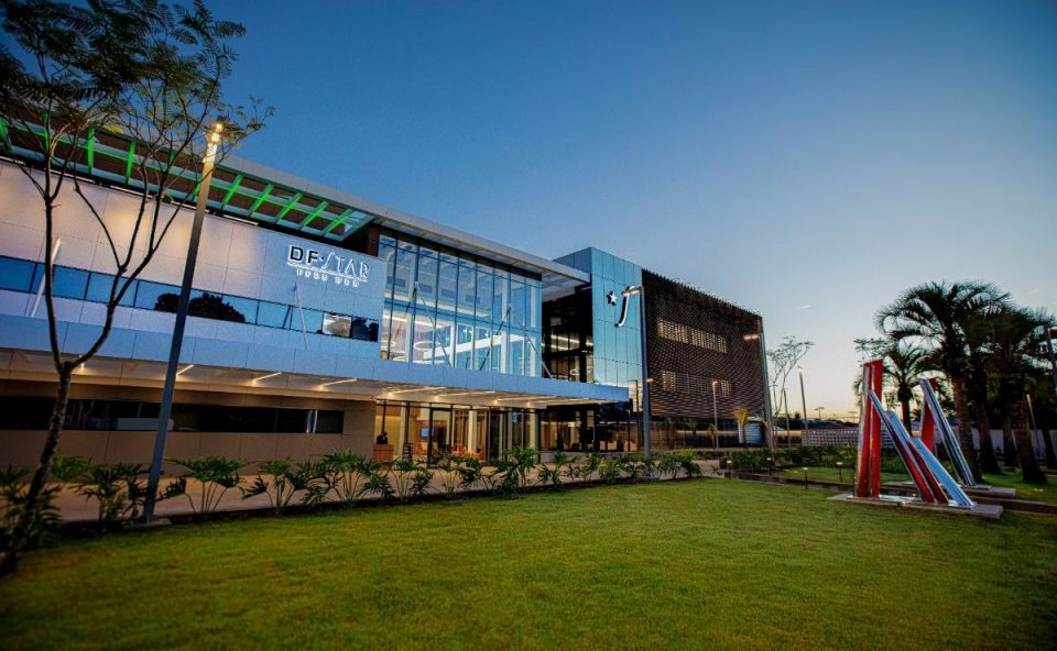 Fachada moderna e iluminada do hospital DF Star em Brasília, da Rede D'Or, durante o entardecer