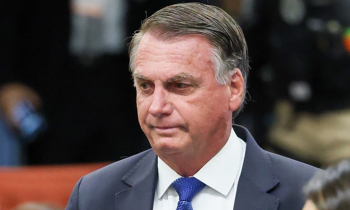 Bolsonaro, um homem de cabelo grisalho e rugas, olha para baixo com expressão preocupada. ele veste terno e gravata