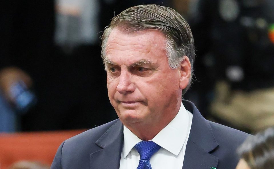 Bolsonaro, um homem de cabelo grisalho e rugas, olha para baixo com expressão preocupada. ele veste terno e gravata