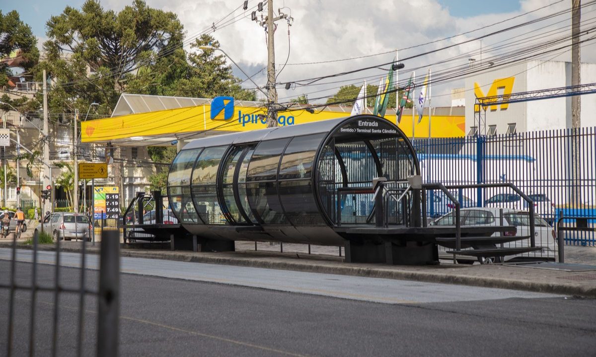 Tubo de ônibus. Ao fundo, um posto de gasolina