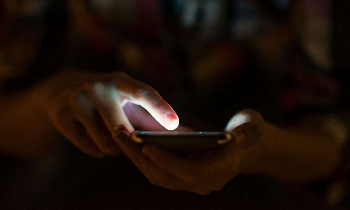 Falso fotógrafo de Curitiba preso por gravar abusos sexuais contra mulheres pode ter feito mais de 700 vítimas. Imagem mostra uma pessoa segurando o celular.