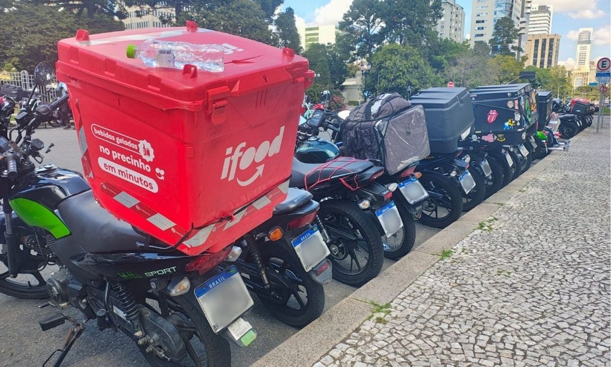 Motos enfileiradas em em frente à calçada. Uma delas tem uma bolsa do Ifood na garupa. Os motoboys estão em protesto em Curitiba devido a um projeto que regulamenta entregas por aplicativo.
