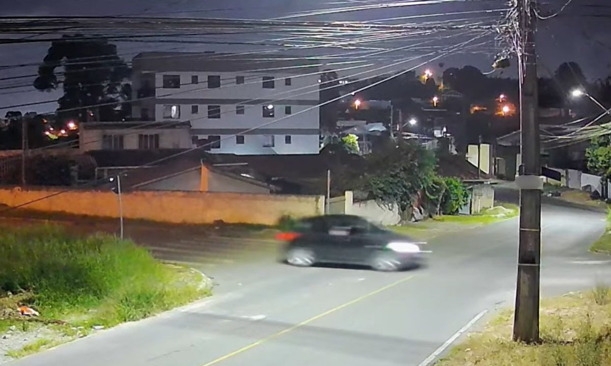 foto de câmera de segurança do momento em que o carro foge em alta velocidade após tiros em colombo. na imagem aparece o carro preto na rua e casa em volta.