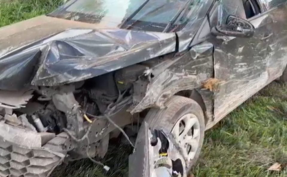 Carro capotou após ser atingido por carga de tijolos na BR-277. Imagem mostra o veículo HB20 preto destruído na parte da frente. O carro está amassado.