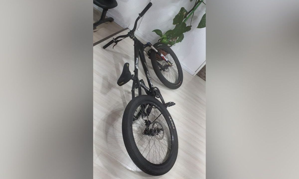 foto da bicicleta do adolescente que foi apreendido após pegar rabeira em ônibus em Curitiba. na imagem aparece a bicicleta preta no chão