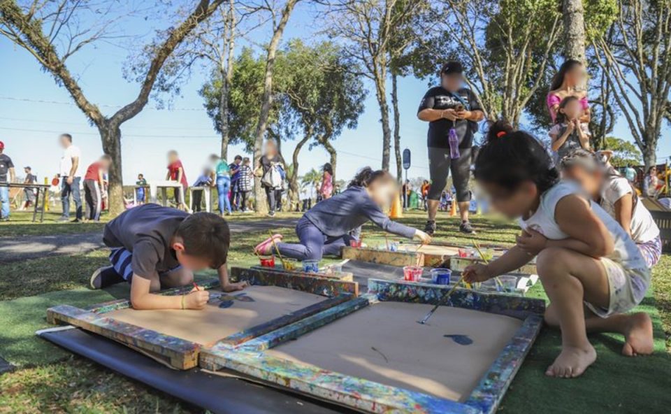 Crianças pintando quadros em um parque de Curitiba, uma das atividades gratuitas disponibilizadas pela Prefeitura.