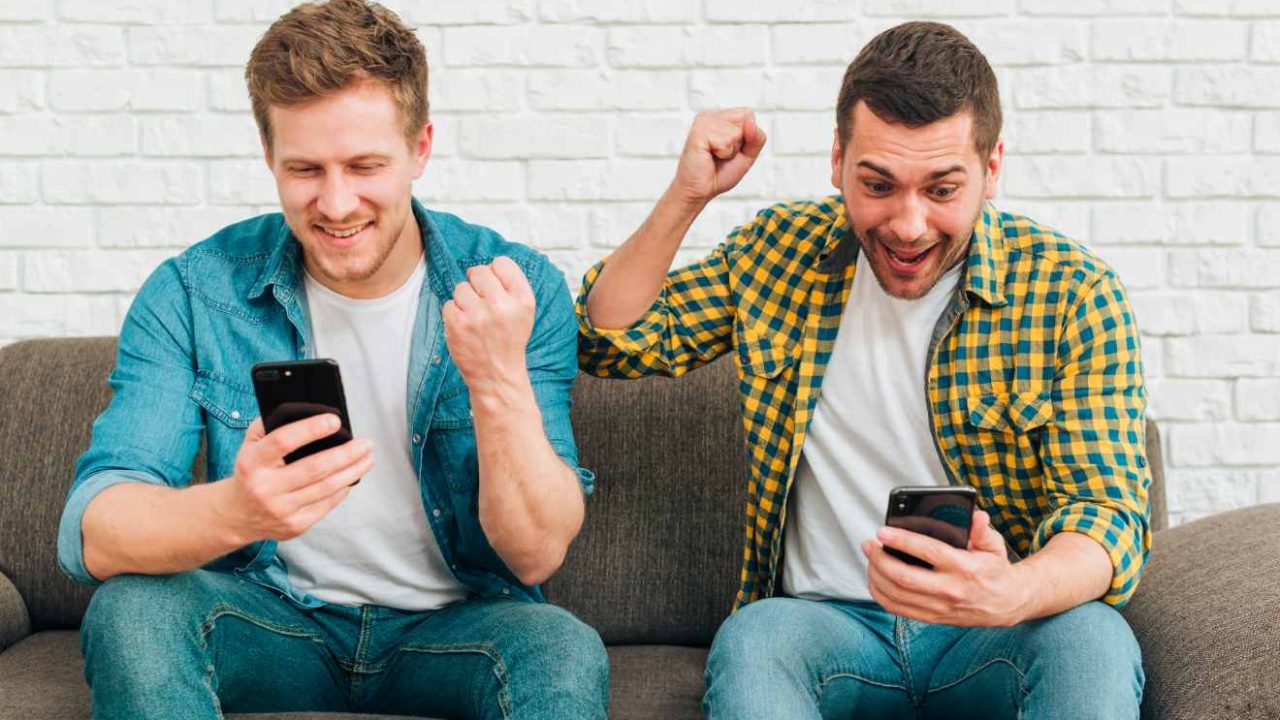 Homens comemorando vendo celular