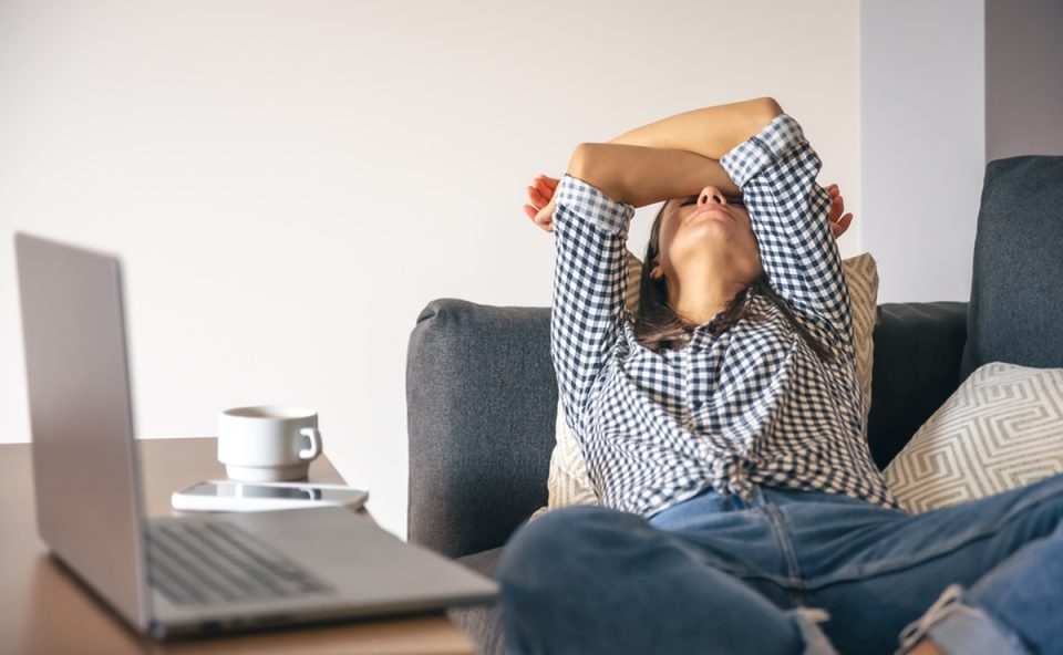 Mulher extremamente cansada em frente ao computador com um café