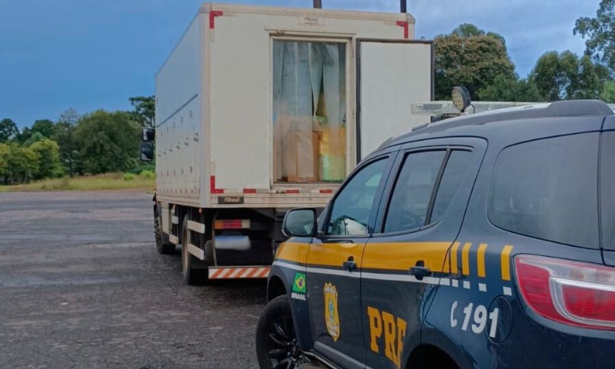 Imagem mostra o caminhão de sorvete carregado com celulares contrabandeados. Veículo está com a porta aberta. Atrás tem uma viatura da Polícia Rodoviária Federal.