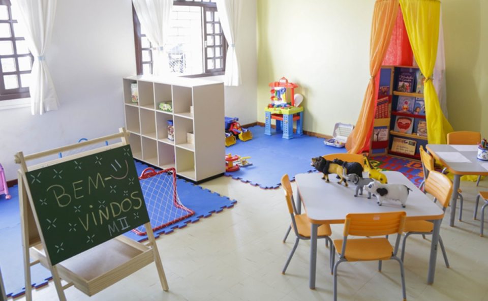 Sala de aula de uma creche em Curitiba e um quadro com a frase 'bem-vindos' escrita com giz de cera. Vagas estão disponíveis.