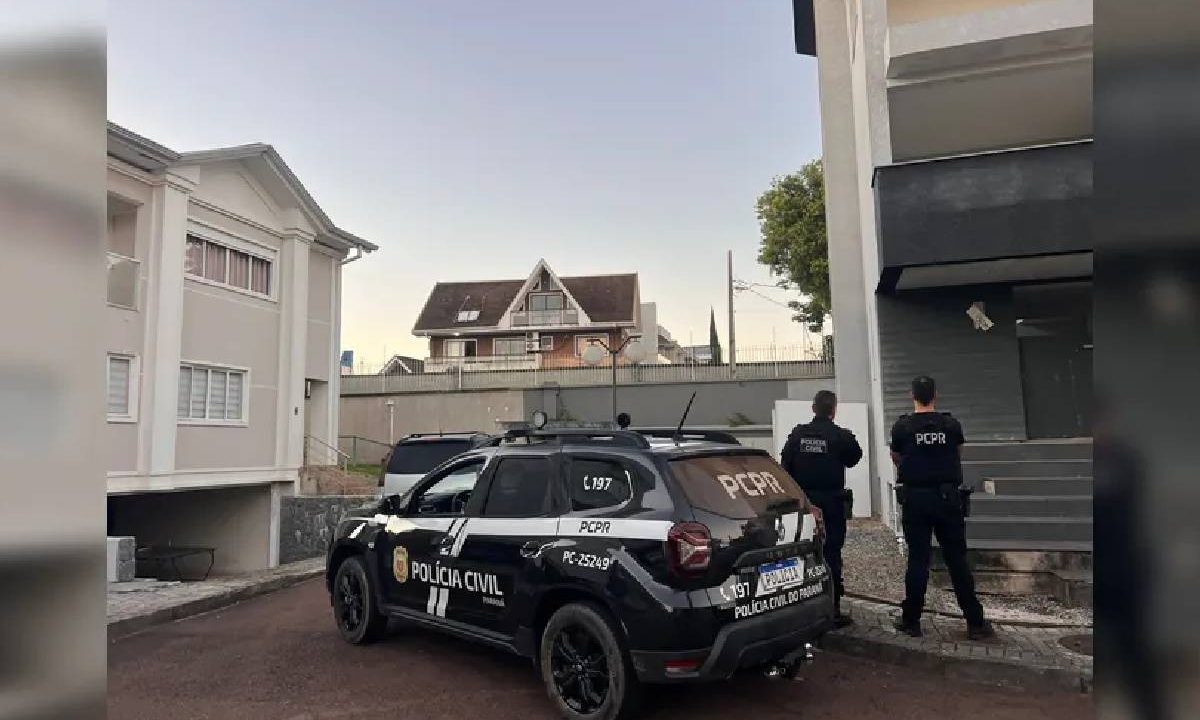 Foto mostra policiais ao lado de viatura dentro de condomínio