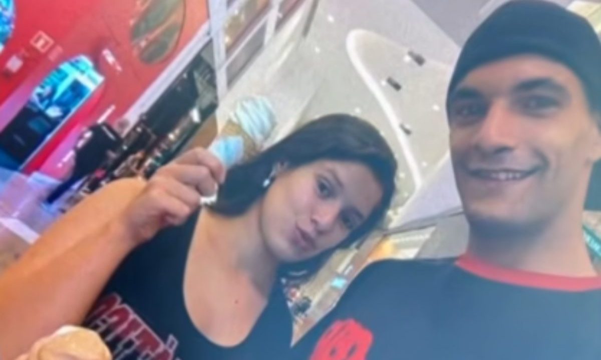 Genro alega que filha adotiva de idoso encontrado morto e esquartejado em Campo Magro foi abusada na infância. Imagem mostra o casal. Ela usa regata preta e tem cabelo preto, faz bico pra foto. Ele usa boné e camiseta preta