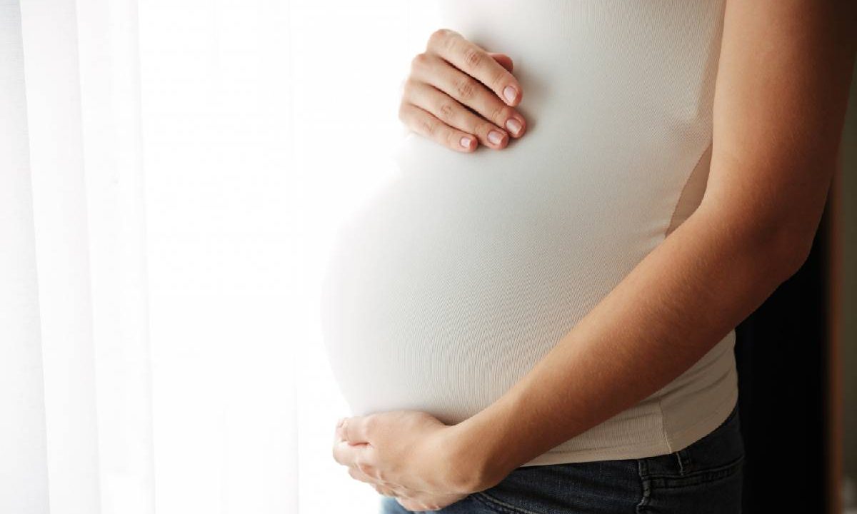 Foto mostra grávida com a mão na barriga