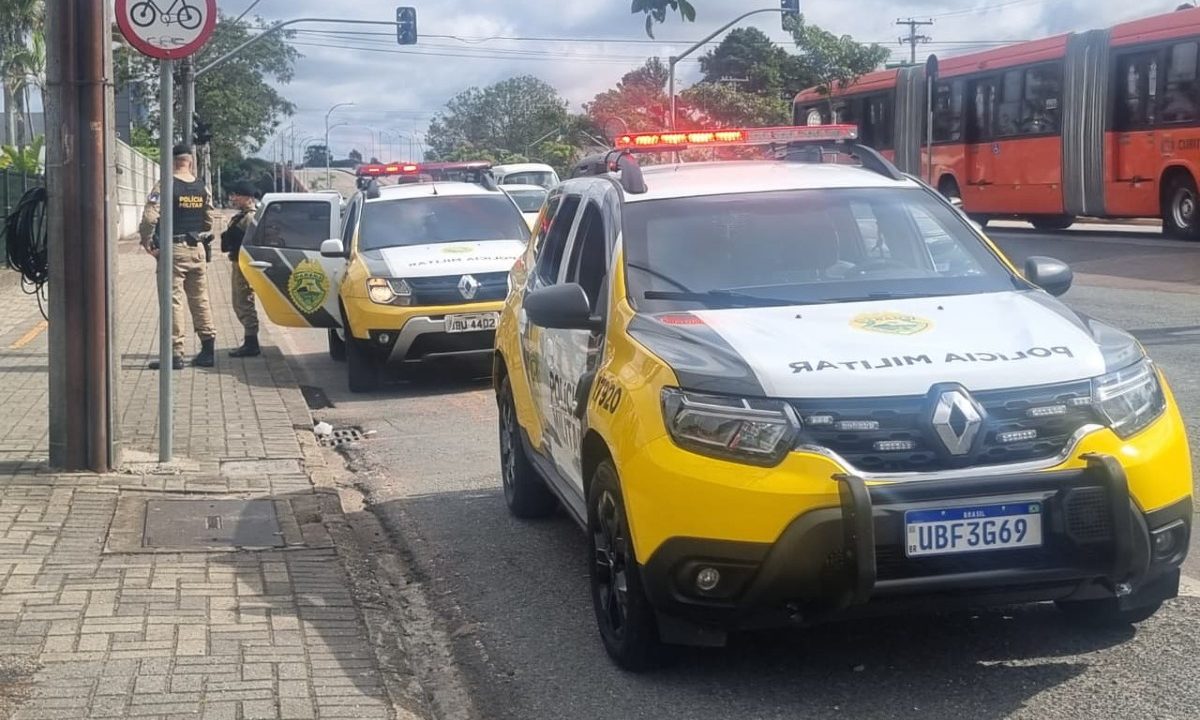 Viatura da Polícia Militar e policiais militares após abordagem de dois suspeitos que assaltaram um homem no terminal de ônibus no bairro Hauer em Curitiba.