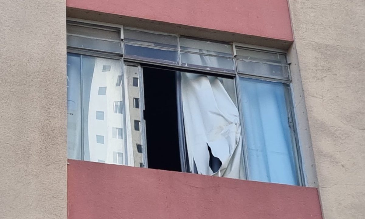 Foto mostra janela de apartamento em Curitiba, de onde homem caiu. Há uma cortina branca