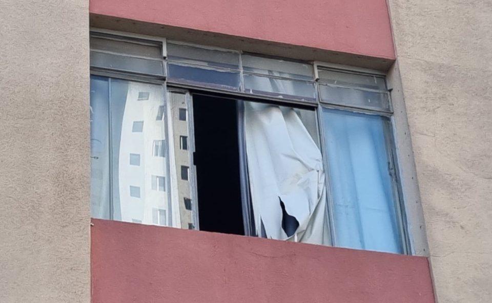 Foto mostra janela de apartamento em Curitiba, de onde homem caiu. Há uma cortina branca