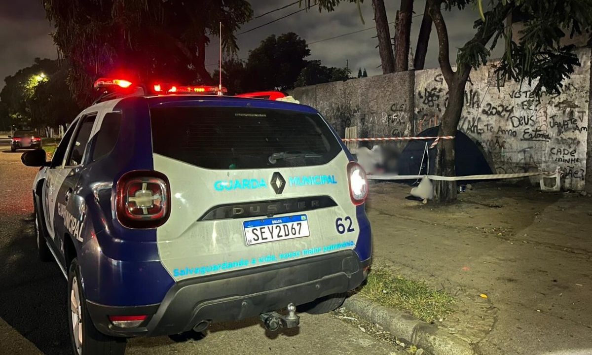 Viatura da Guarda Municipal de Curitiba estacionada em rua no bairro Parolin, após agentes encontrarem homem morto com tiros na cabeça, sentado em calçada.