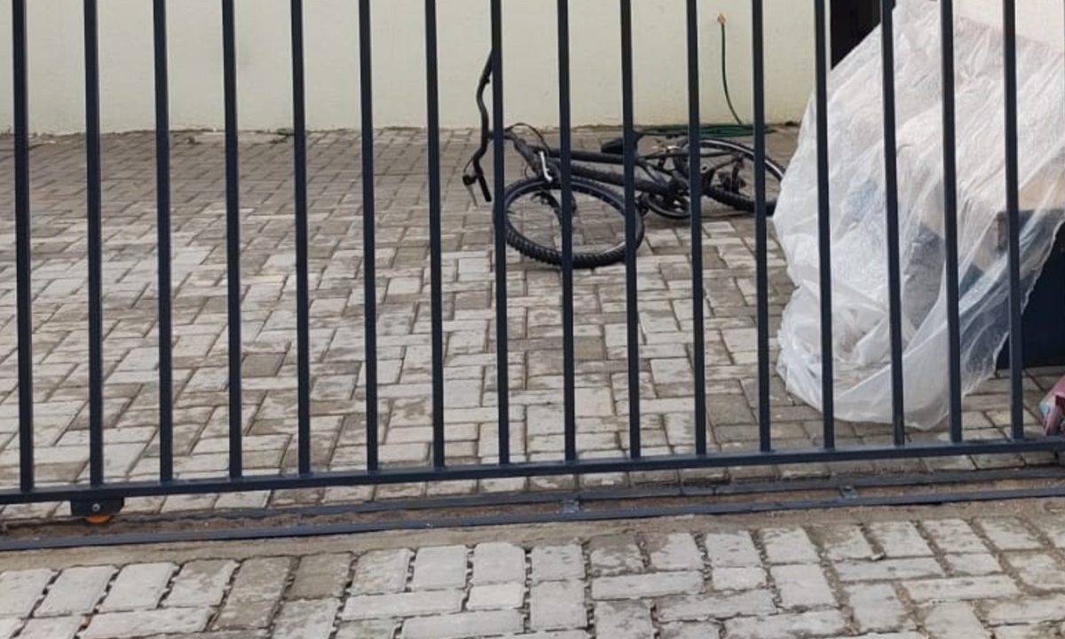 Portão da casa onde mulher foi baleada pelo ex-companheiro no bairro Caximba, em Curitiba; uma bicicleta aparece dentro do terreno da residência.