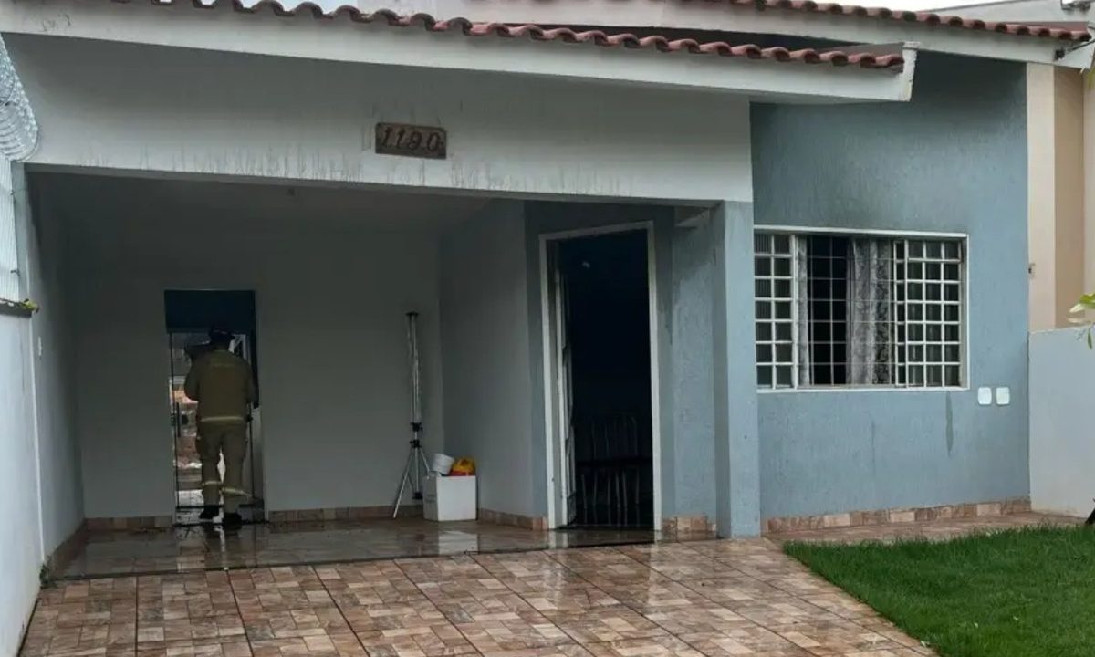 Foto mostra casa incendiada pelo homem que matou a ex-companheira queimada por não aceitar o fim do relacionamento. A casa é azul claro e um bombeiro aparece entrando no imóvel